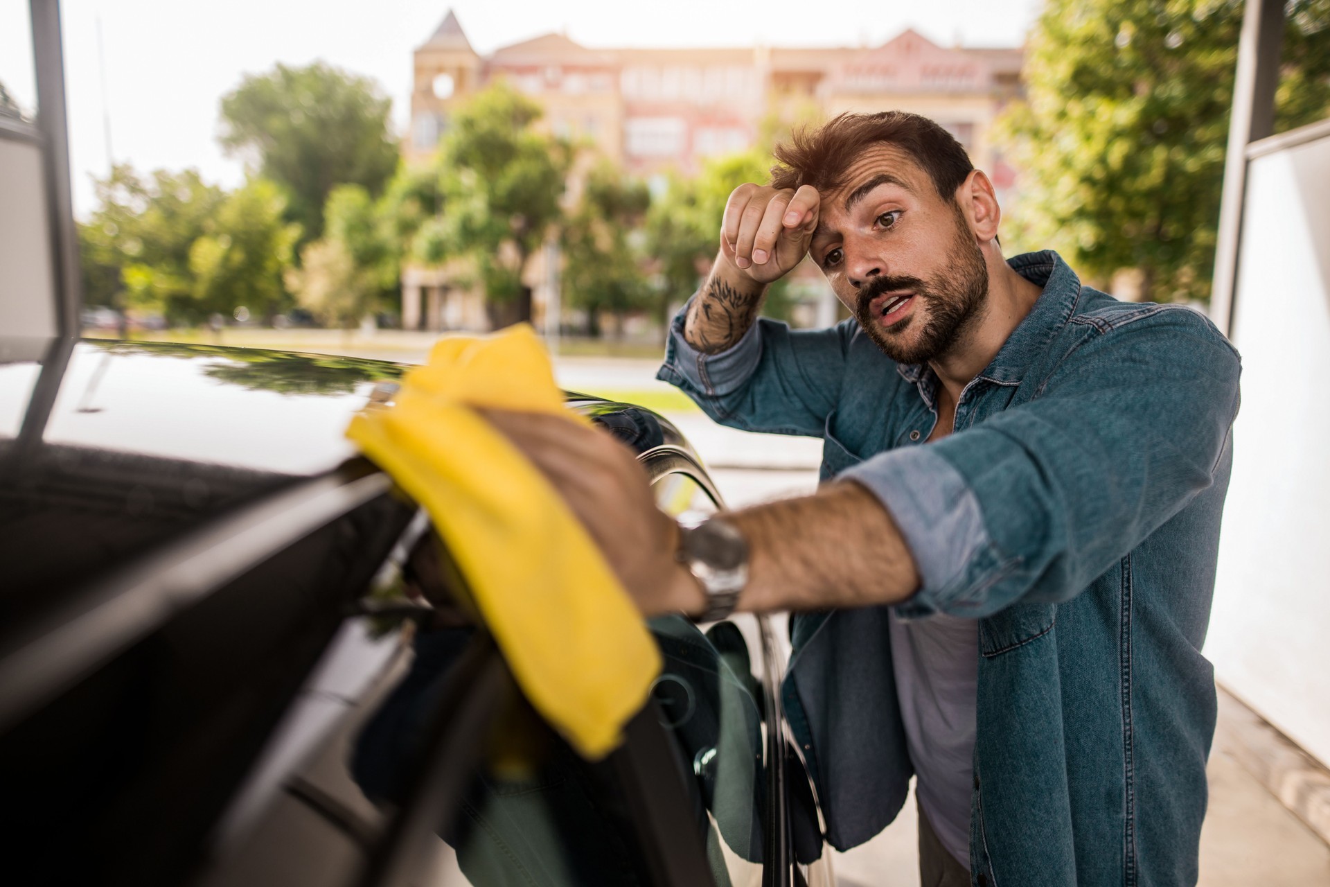 Young man wiping his car at outdoor car wash.